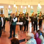Blaskapelle in grünen Westen spielt beim Oktoberfest im Foyer des Mediana Pflegestifts Fulda, im Vordergrund Bewohnerinnen und Bewohner