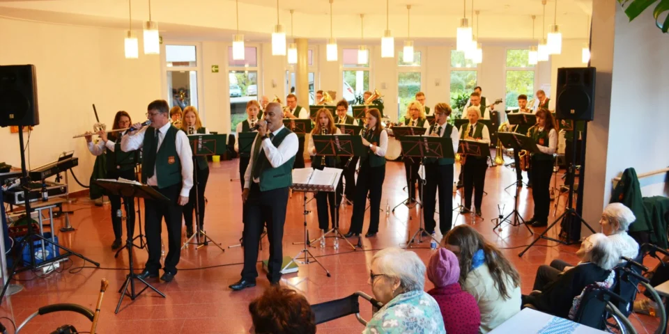 Blaskapelle in grünen Westen spielt beim Oktoberfest im Foyer des Mediana Pflegestifts Fulda, im Vordergrund Bewohnerinnen und Bewohner