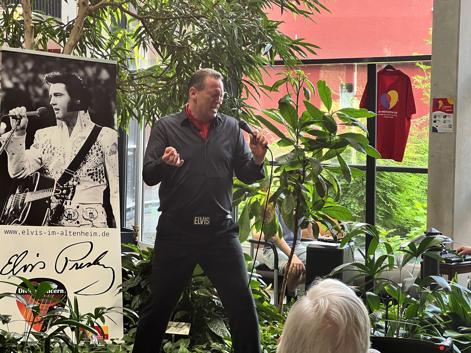 Elvis-Interpret Christian Gutsch singt mit Mikrofon beim Hessentagskonzert im Foyer des Mediana Pflegestifts in Fulda