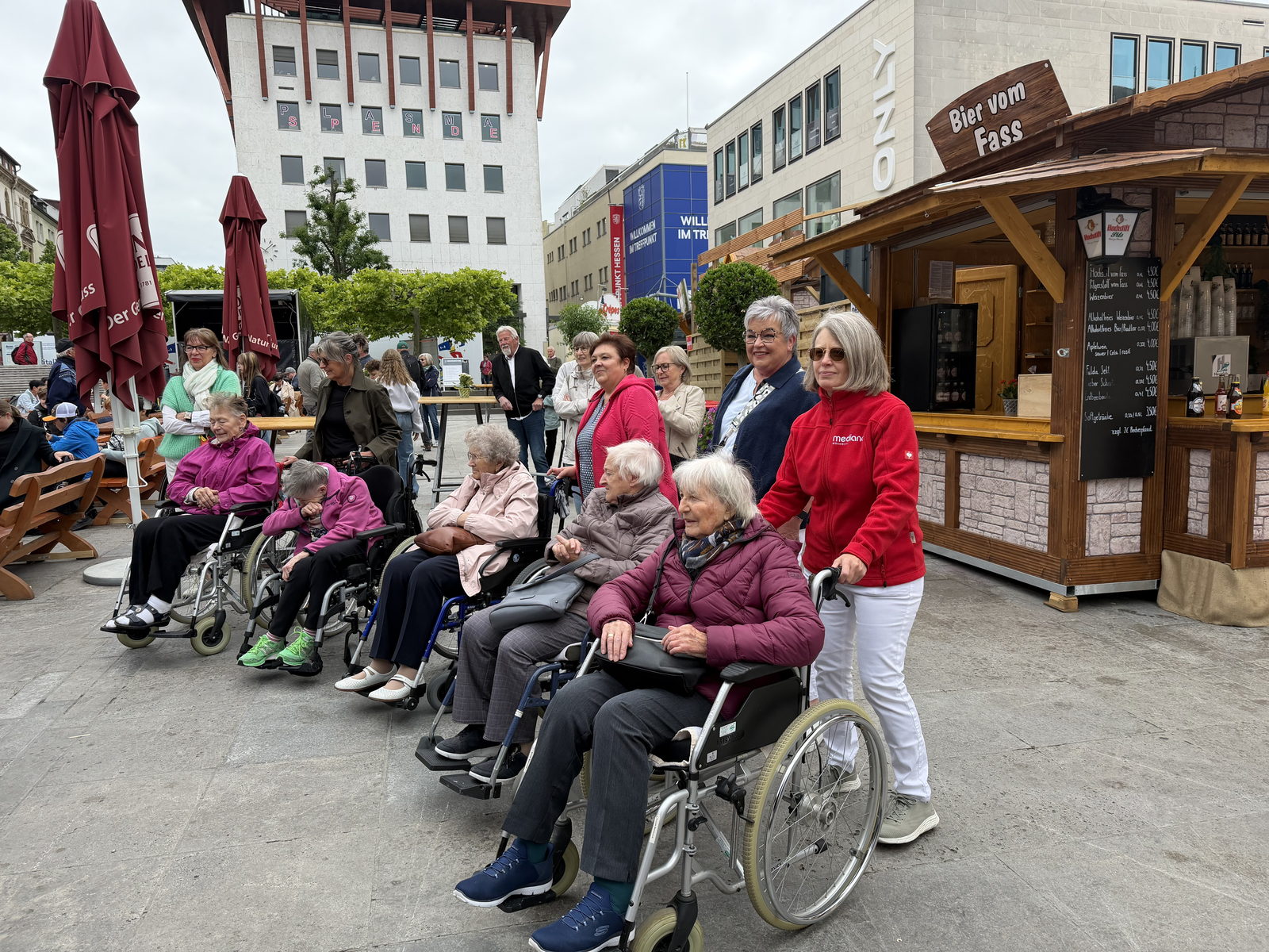 Eine Mitarbeiterin der Sozialen Betreuung begleitet eine Bewohnergruppe im Rollstuhl über den Hessentag in der Fuldaer Innenstadt